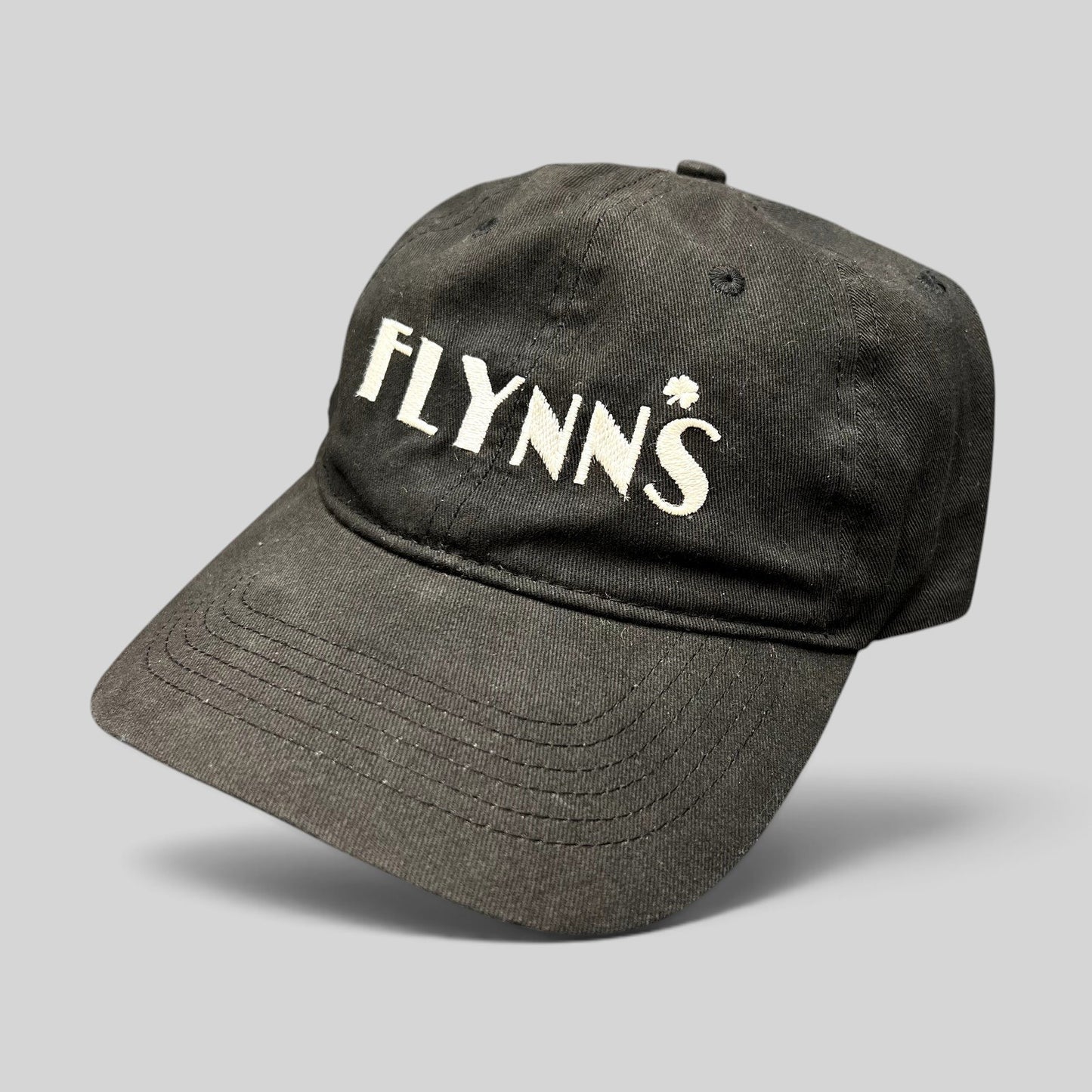 Raree Finds black unstructured strapback hat with white embroidered Flynn’s Irish pub logo and shamrock accent.