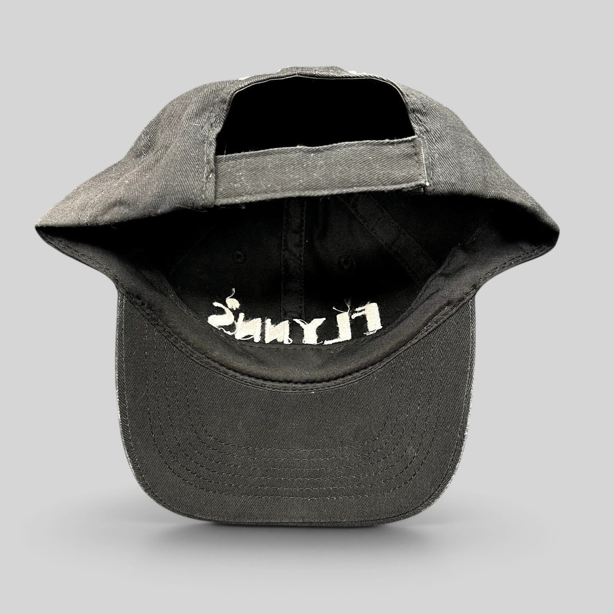 Raree Finds black unstructured strapback hat with white embroidered Flynn’s logo and shamrock detail, back view