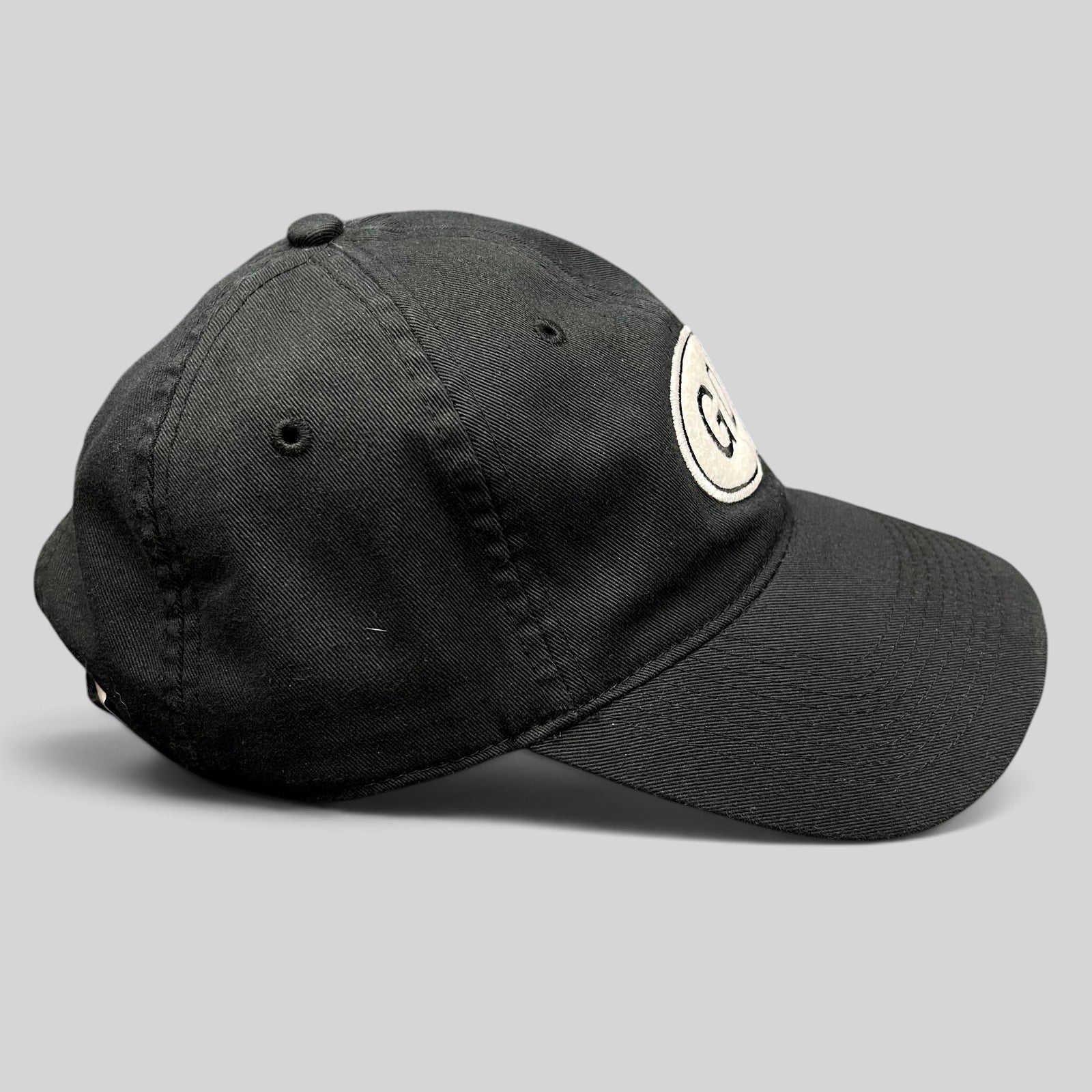 Raree Finds black cotton strapback hat featuring a white oval GD logo patch on the front side profile view