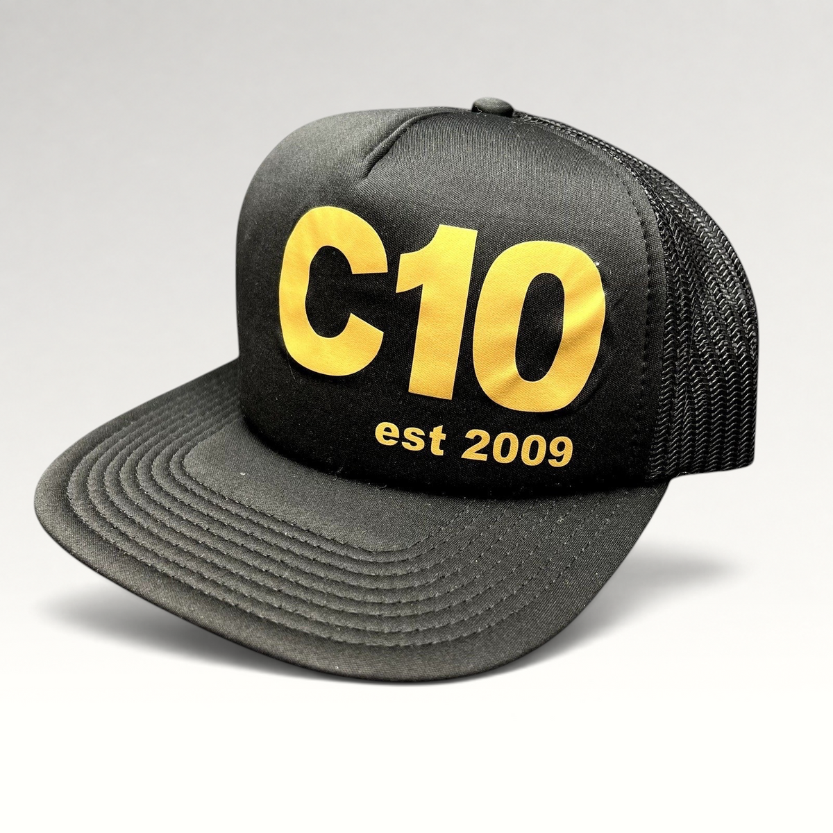 Raree Finds black and gold C10 trucker snapback hat with foam front, mesh back, and structured high crown profile.