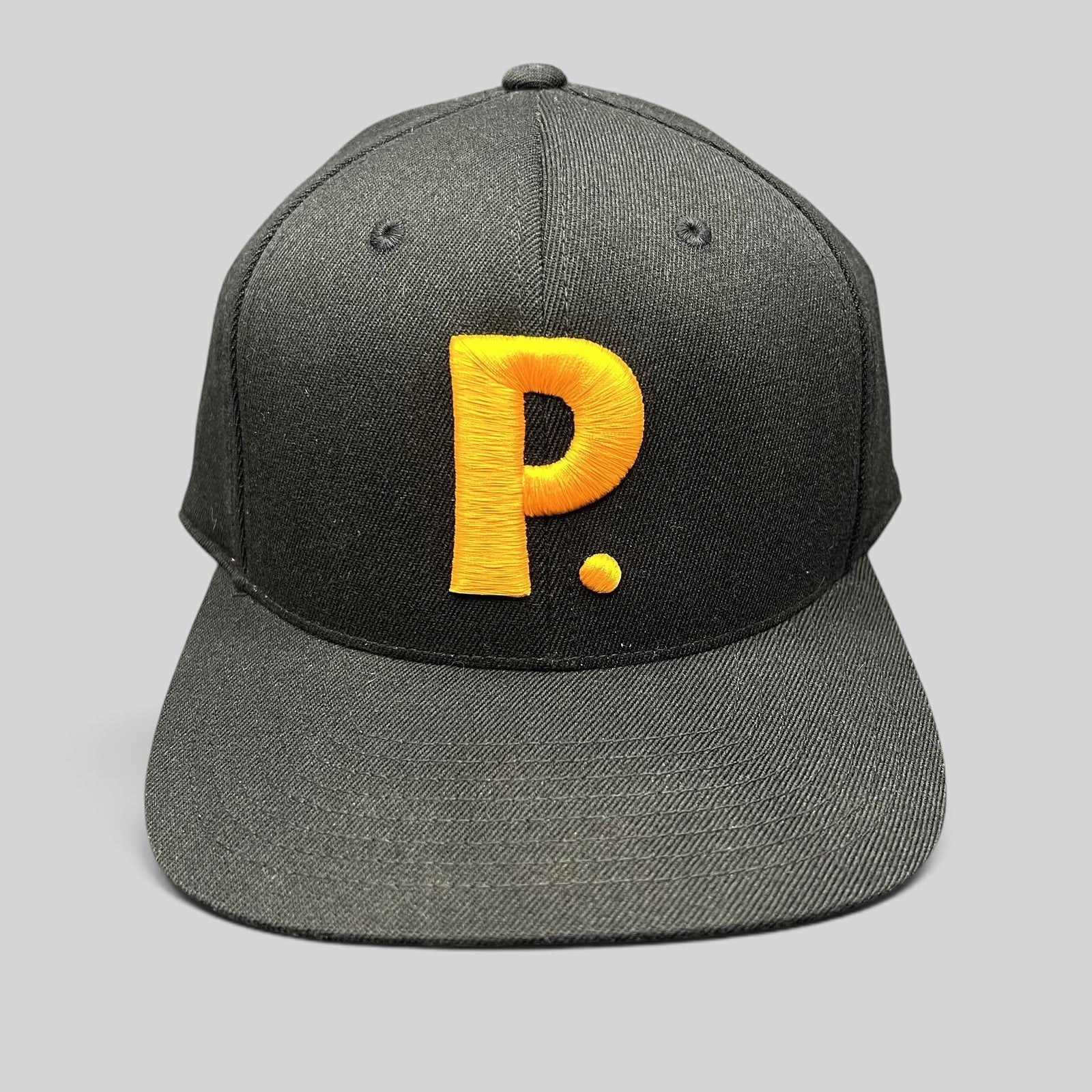 Raree Finds black Yupoong 110 Flexfit snapback hat featuring a large gold embroidered P logo on the front crown.