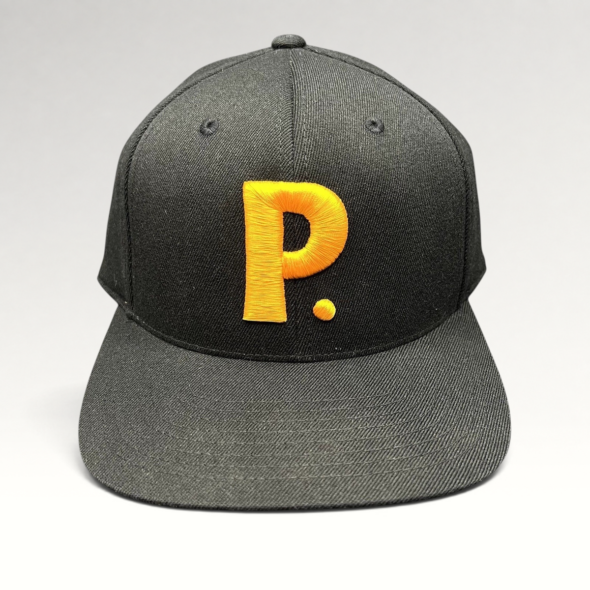 Raree Finds black Yupoong 110 Flexfit snapback hat featuring a large gold embroidered P logo on the front crown.
