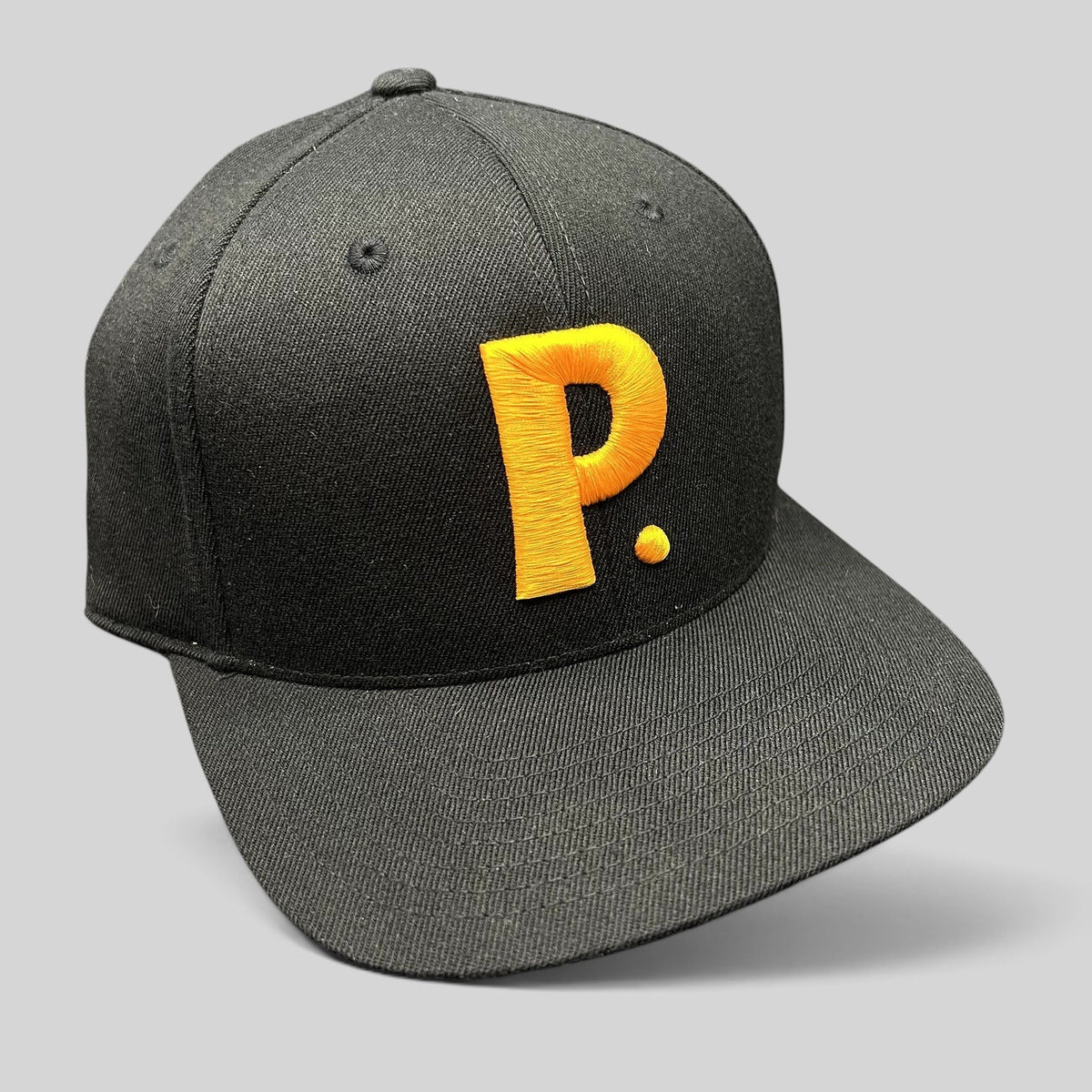 Raree Finds black Yupoong 110 Flexfit snapback hat featuring a bold gold embroidered P logo on the structured crown