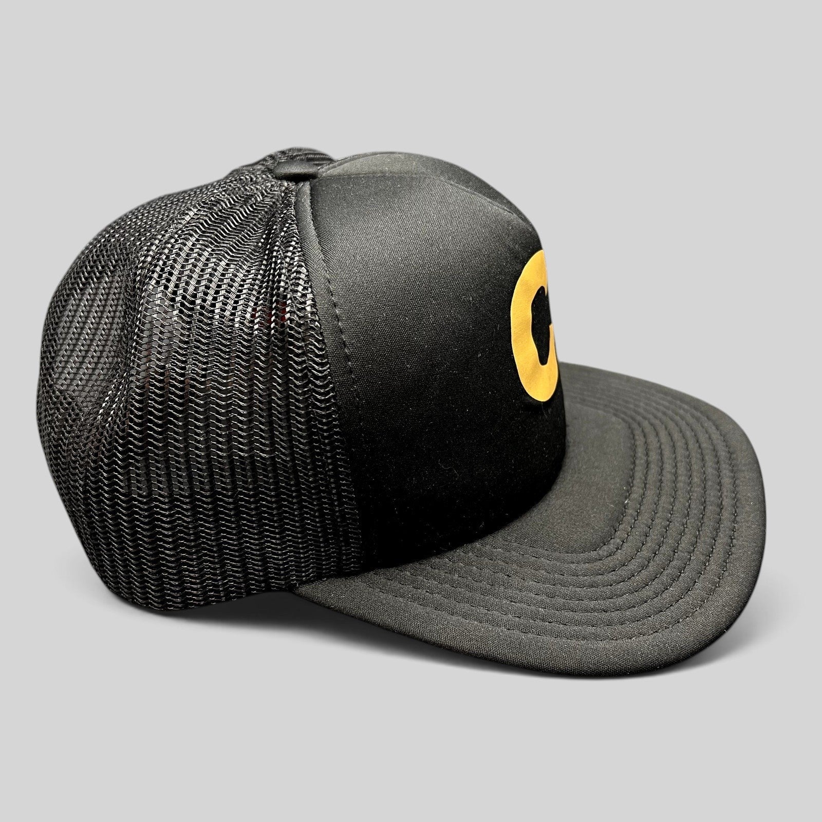 Raree Finds Cloud 10 C10 black and gold trucker hat with foam front, mesh back panels, and structured high crown.