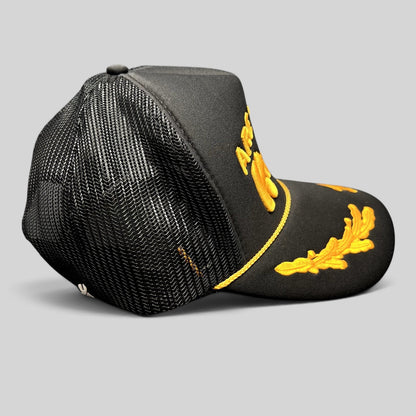 Raree Finds black and gold trucker hat with raised embroidery, gold rope detail, and leaf accents on the bill.