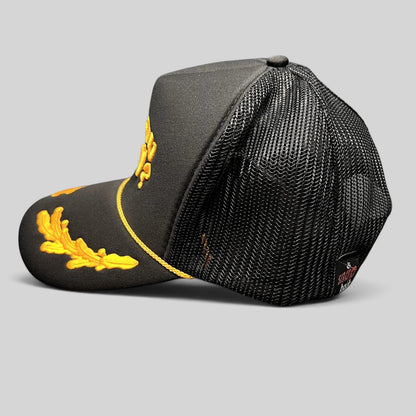 Raree Finds Are You Kozy? black trucker hat with gold embroidered leaf accents, rope detail, and mesh back panels.