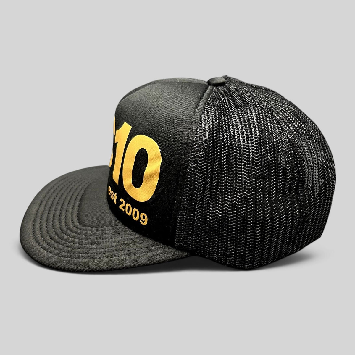 Raree Finds Cloud 10 C10 black and gold trucker hat with foam front, mesh back, and structured high crown profile.