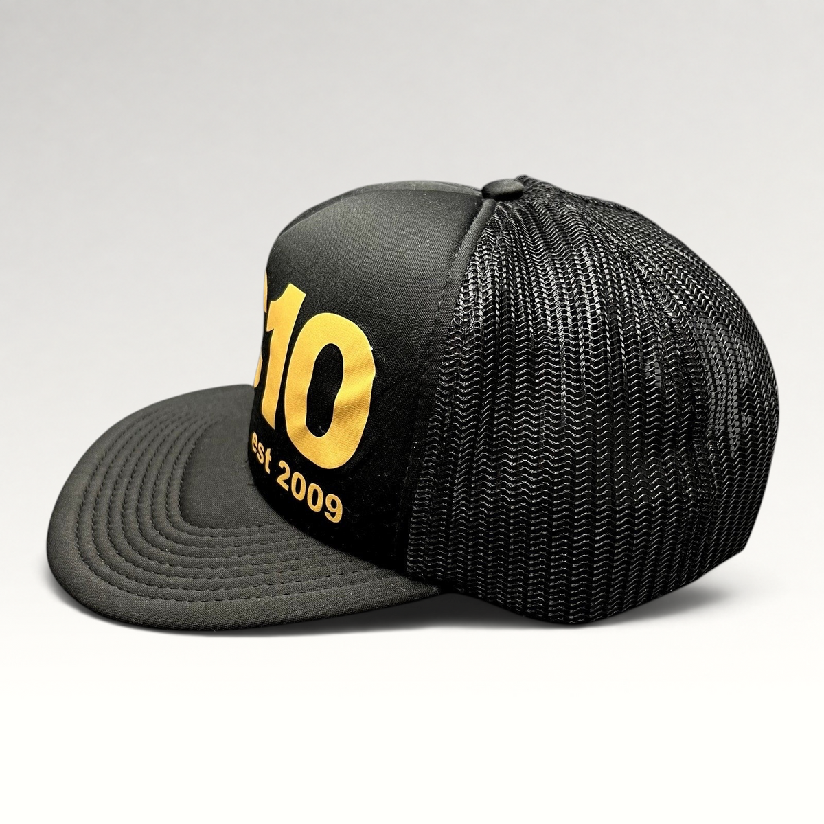 Raree Finds Cloud 10 C10 black and gold trucker hat with foam front, mesh back, and structured high crown profile.
