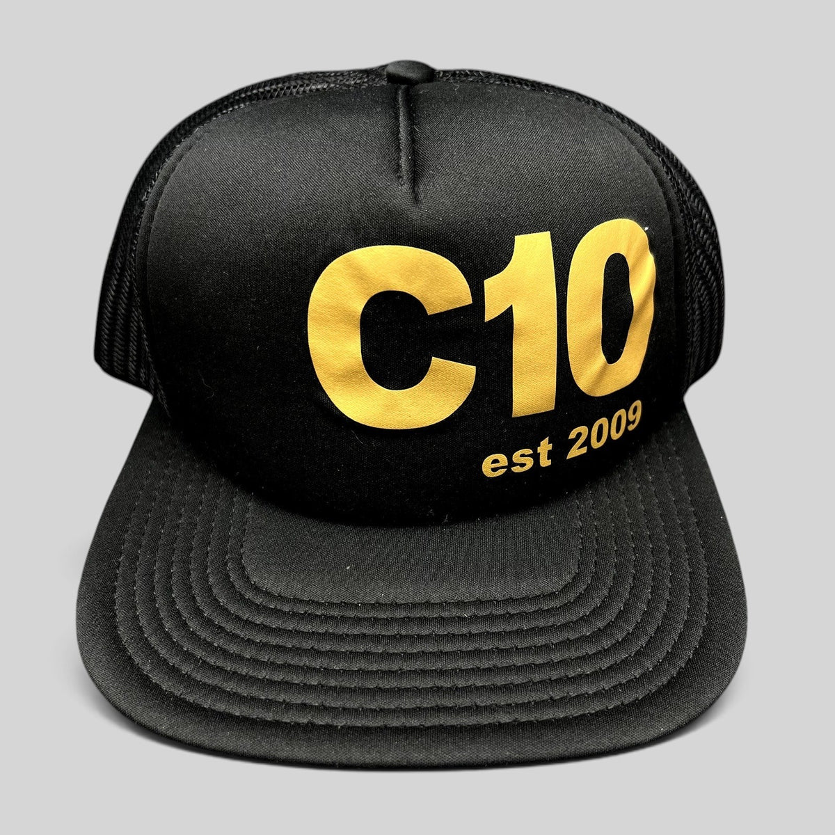 Raree Finds black Otto trucker snapback hat with gold C10 graphic and mesh back panels.