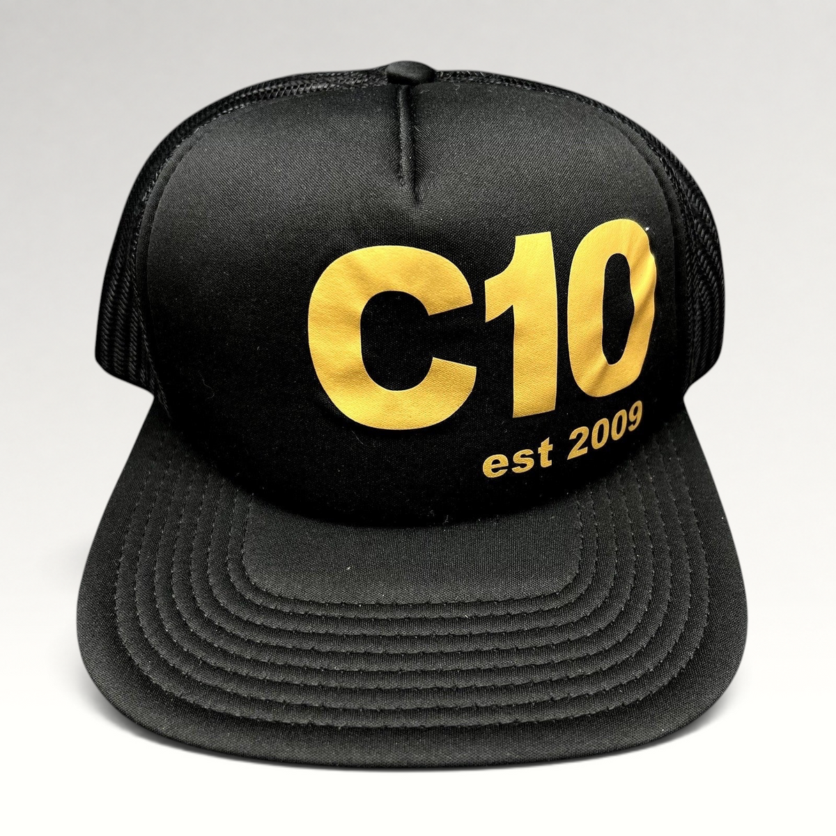 Raree Finds black Otto trucker snapback hat with gold C10 graphic and mesh back panels.