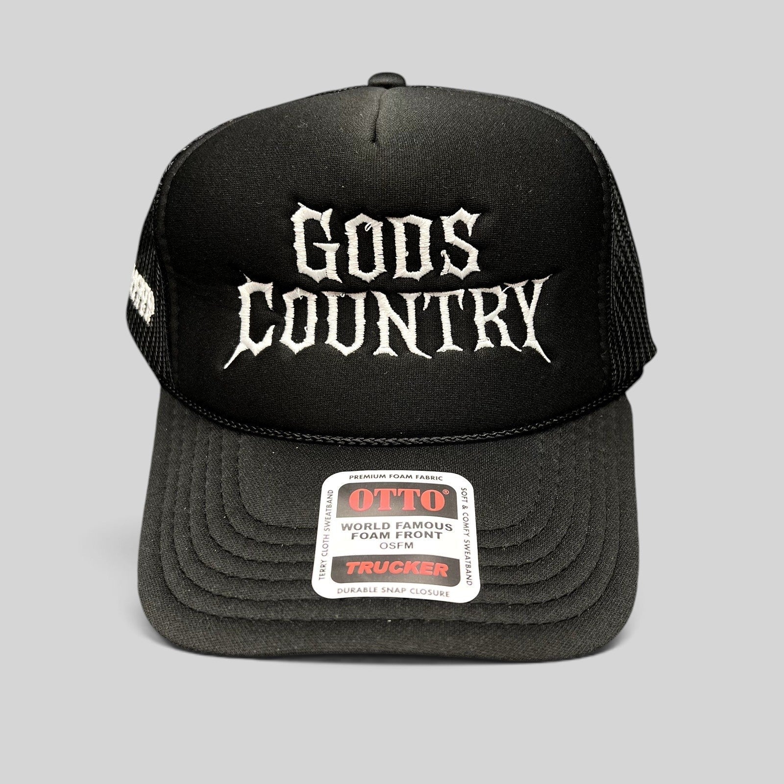 Raree Finds black trucker hat with white gothic God's Country embroidery, foam front, and mesh back.