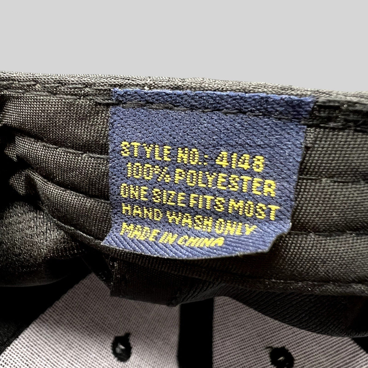 Raree Finds black hat interior tag showing 100 percent polyester material and care instructions