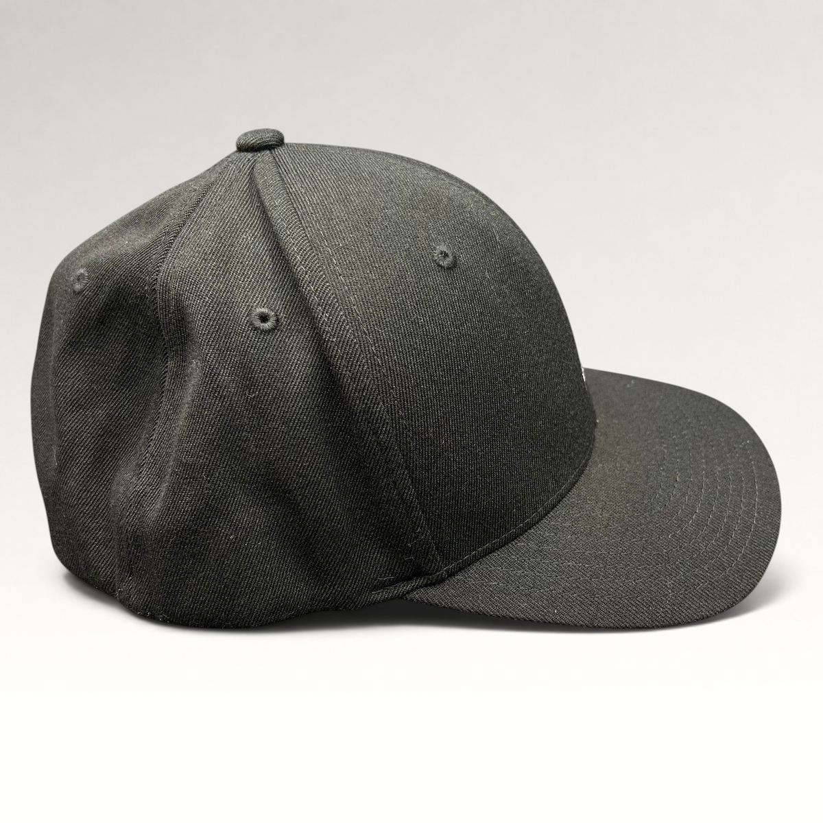 Raree Finds black Kangol flexfit baseball cap with a structured crown and curved brim in a side profile view.