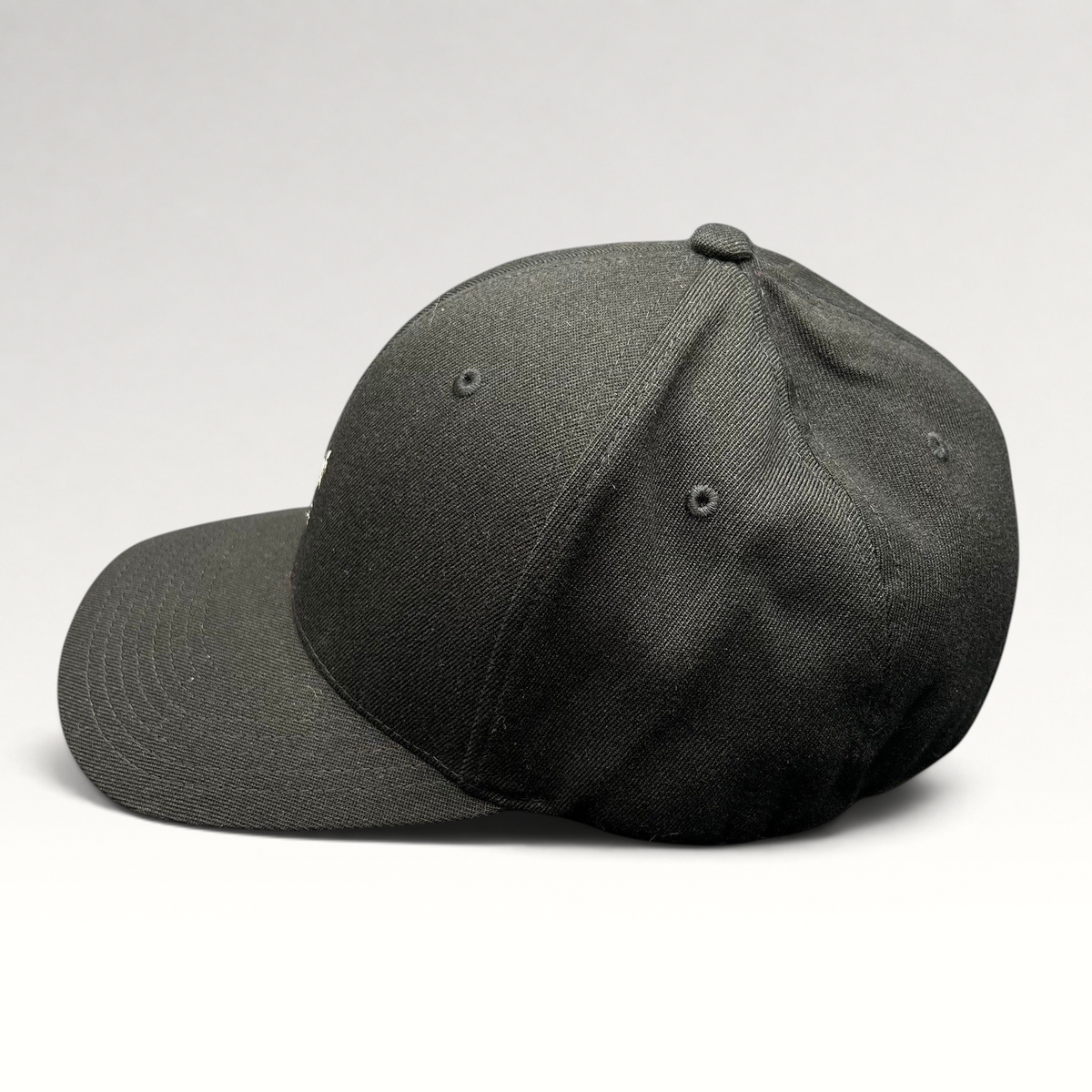 Raree Finds black Kangol flexfit baseball cap with a structured crown and curved brim shown from the side profile.