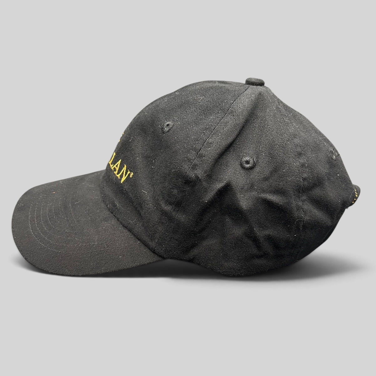 Raree Finds black The Macallan Scotch Whisky strapback hat with gold embroidery, side profile view.