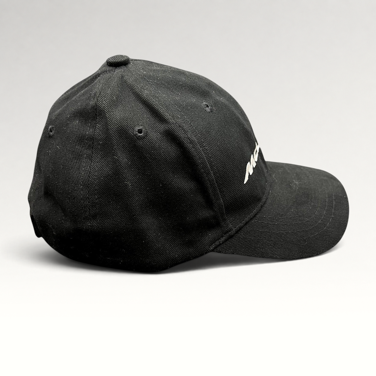 Raree Finds black McLaren cotton strapback hat with white embroidered logo, side profile view of 6-panel cap.