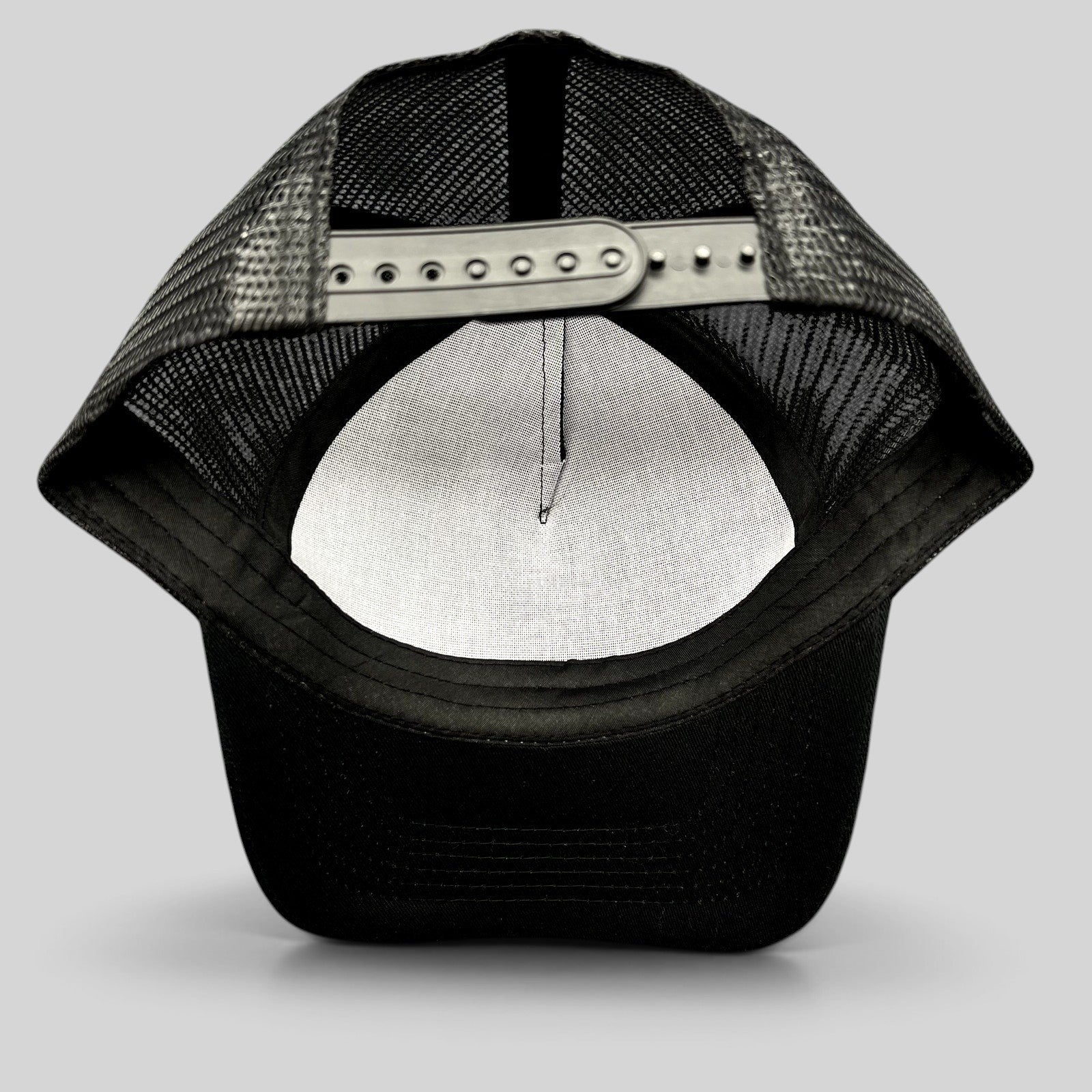Raree Finds black mesh trucker hat showing the adjustable snapback closure and interior crown view