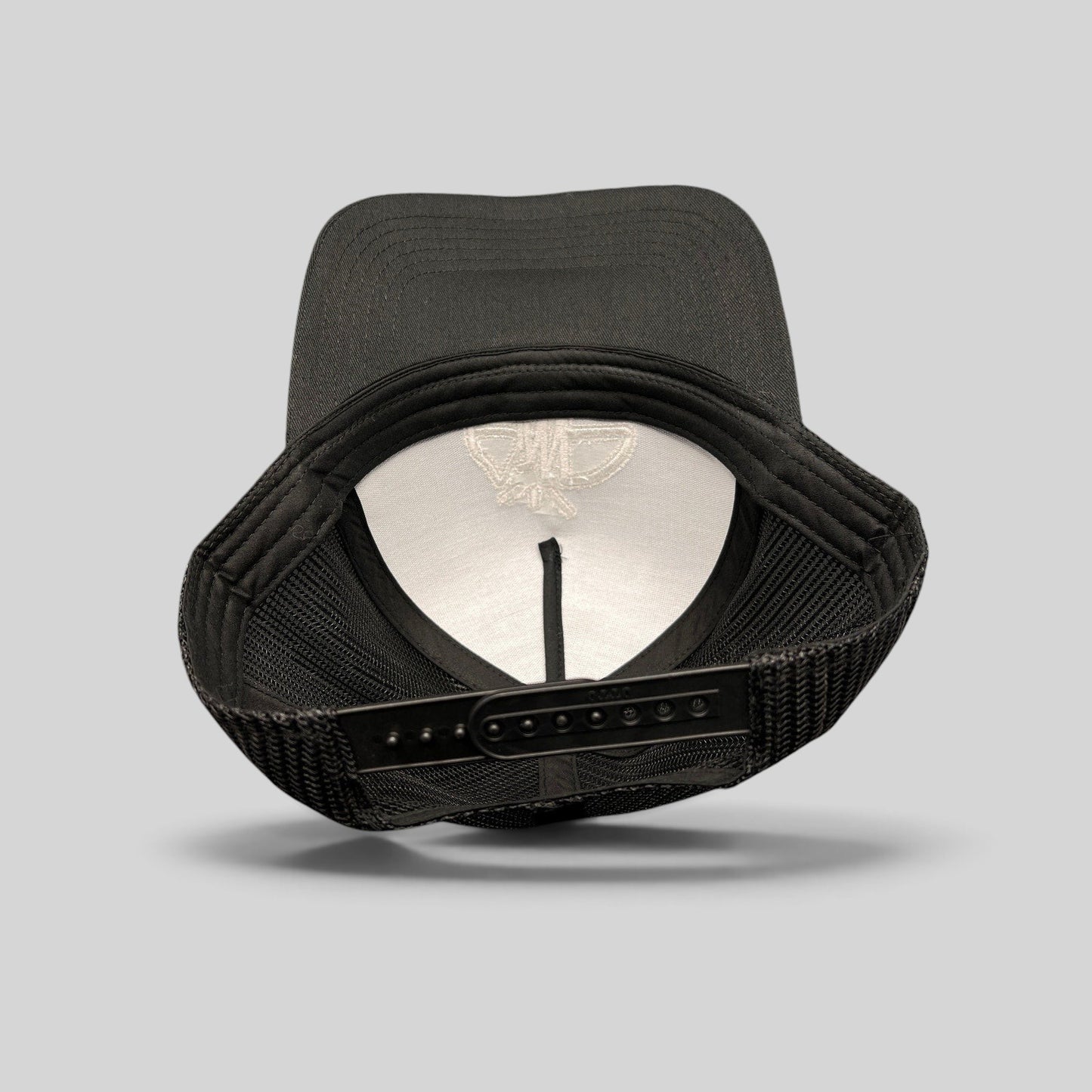 Raree Finds black mesh trucker hat showing the interior structure, adjustable snapback closure, and embroidered logo.