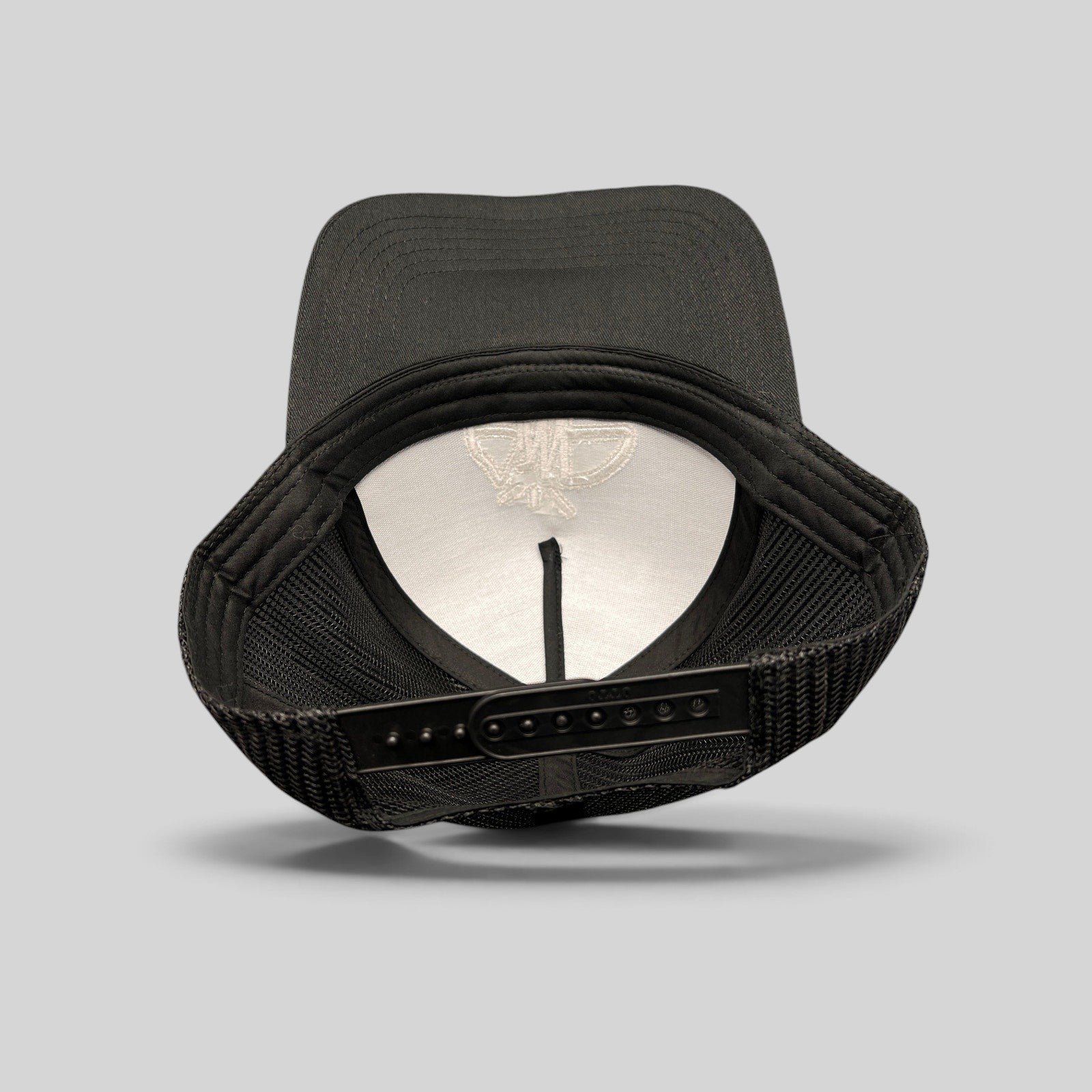 Raree Finds black mesh trucker hat showing the interior structure, adjustable snapback closure, and embroidered logo.