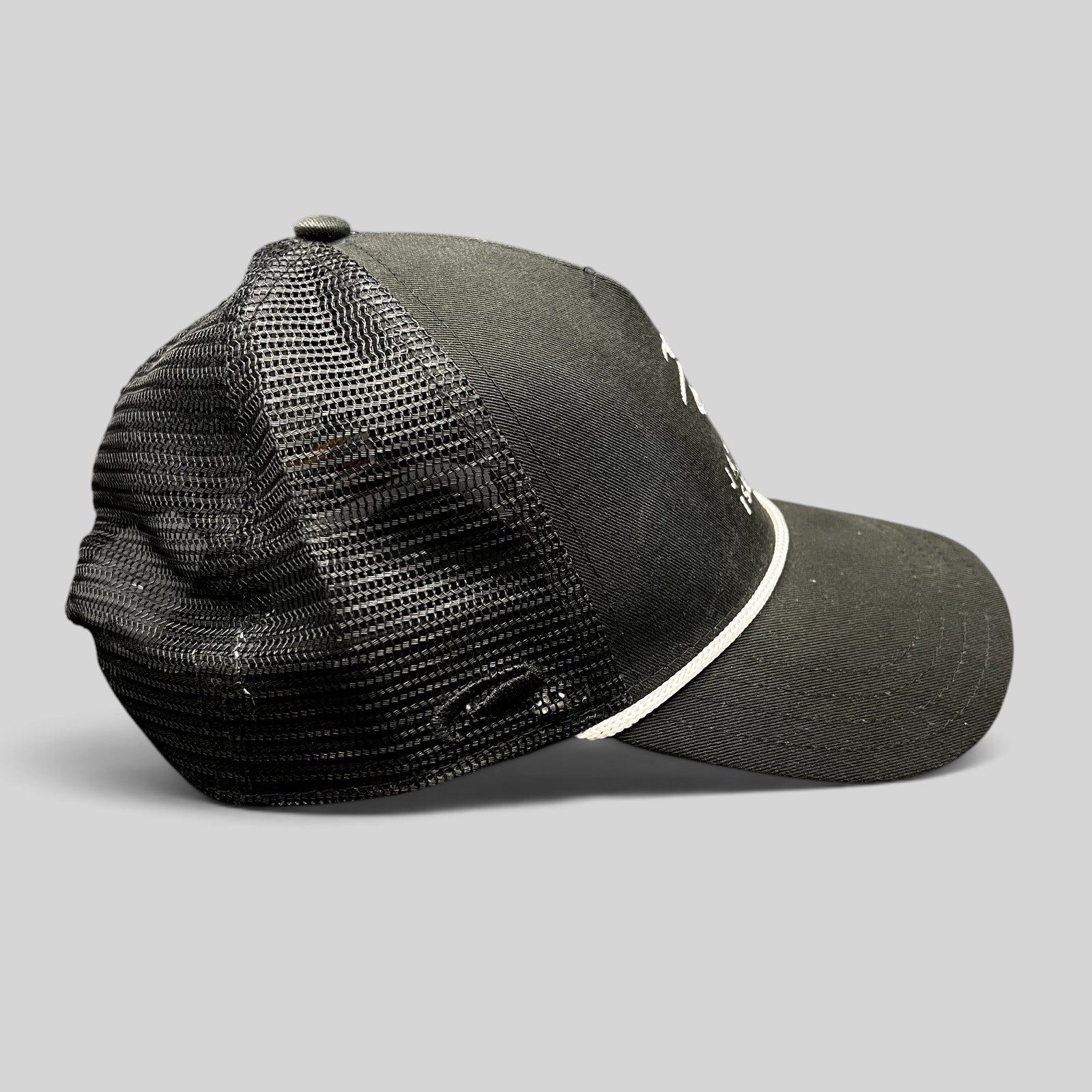 Raree Finds black trucker hat with mesh back, white embroidered coastal logo, and adjustable snapback closure.