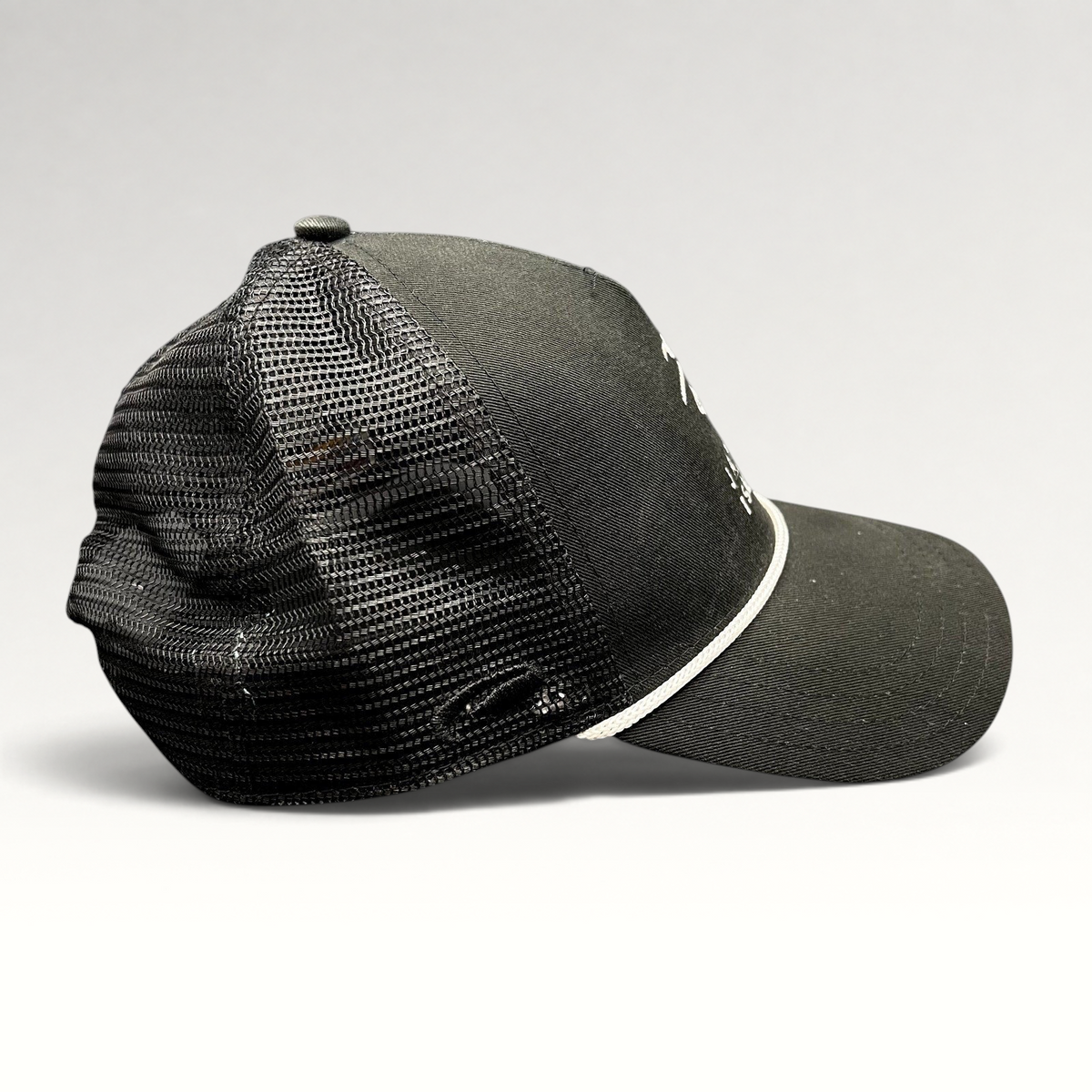 Raree Finds black trucker hat with mesh back, white embroidered coastal logo, and adjustable snapback closure.