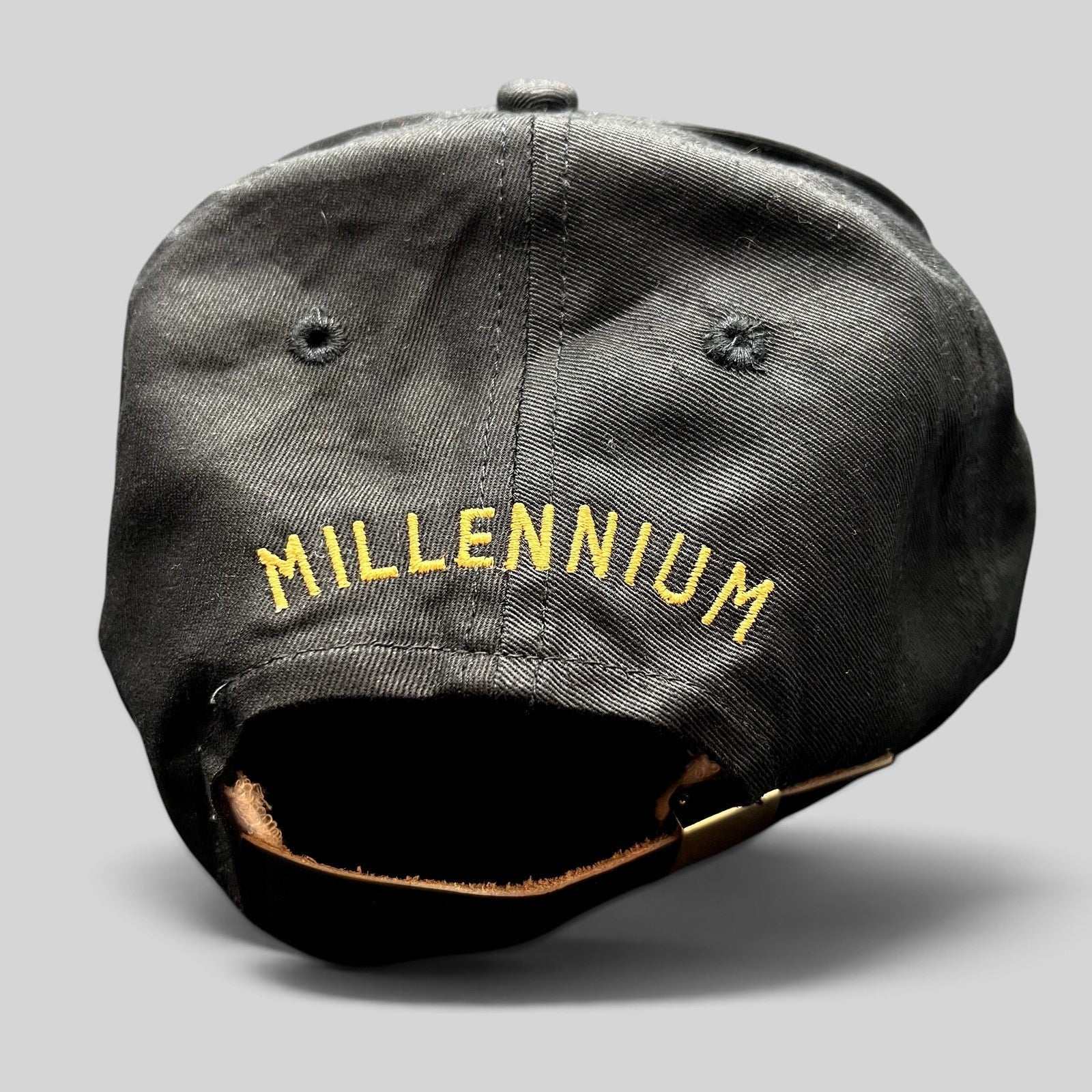 Raree Finds vintage black strapback hat with gold Millennium embroidery on the back and brass-tone hardware.