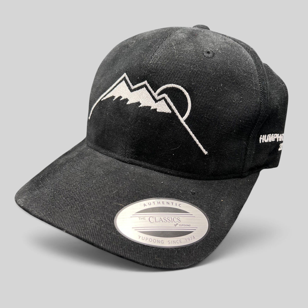 Raree Finds black Yupoong strapback hat featuring a white embroidered Humphreys Peak mountain and sun graphic