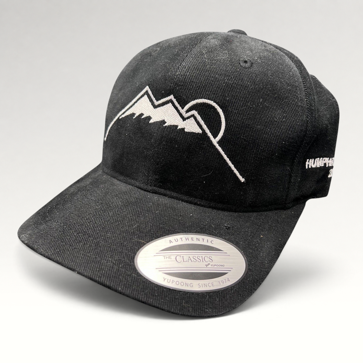Raree Finds black Yupoong strapback hat featuring a white embroidered Humphreys Peak mountain and sun graphic