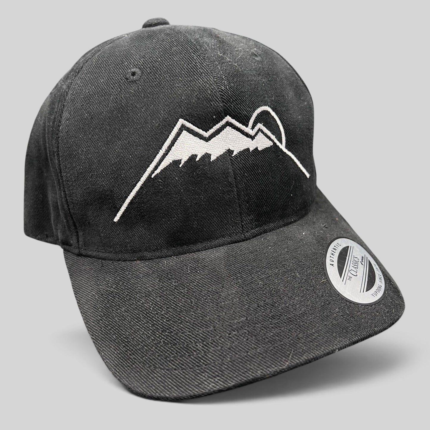 Raree Finds black Yupoong strapback hat featuring a white embroidered Humphreys Peak mountain and sun graphic.