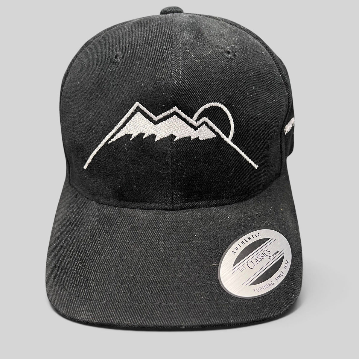 Raree Finds black Yupoong strapback hat featuring a white embroidered Humphreys Peak mountain and sun graphic