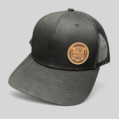 Raree Finds black American Ninja Warrior crew trucker snapback hat with a circular leatherette patch and mesh back.