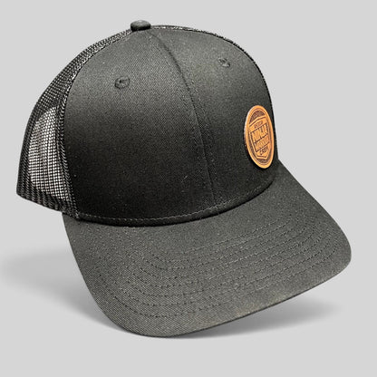 Raree Finds black American Ninja Warrior crew trucker hat with a circular leatherette patch and mesh back panels.