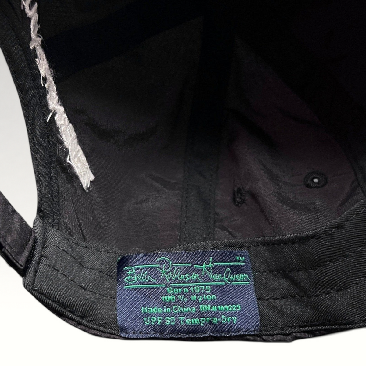 Raree Finds black nylon hat interior label showing brand details and UPF 50 fabric specifications