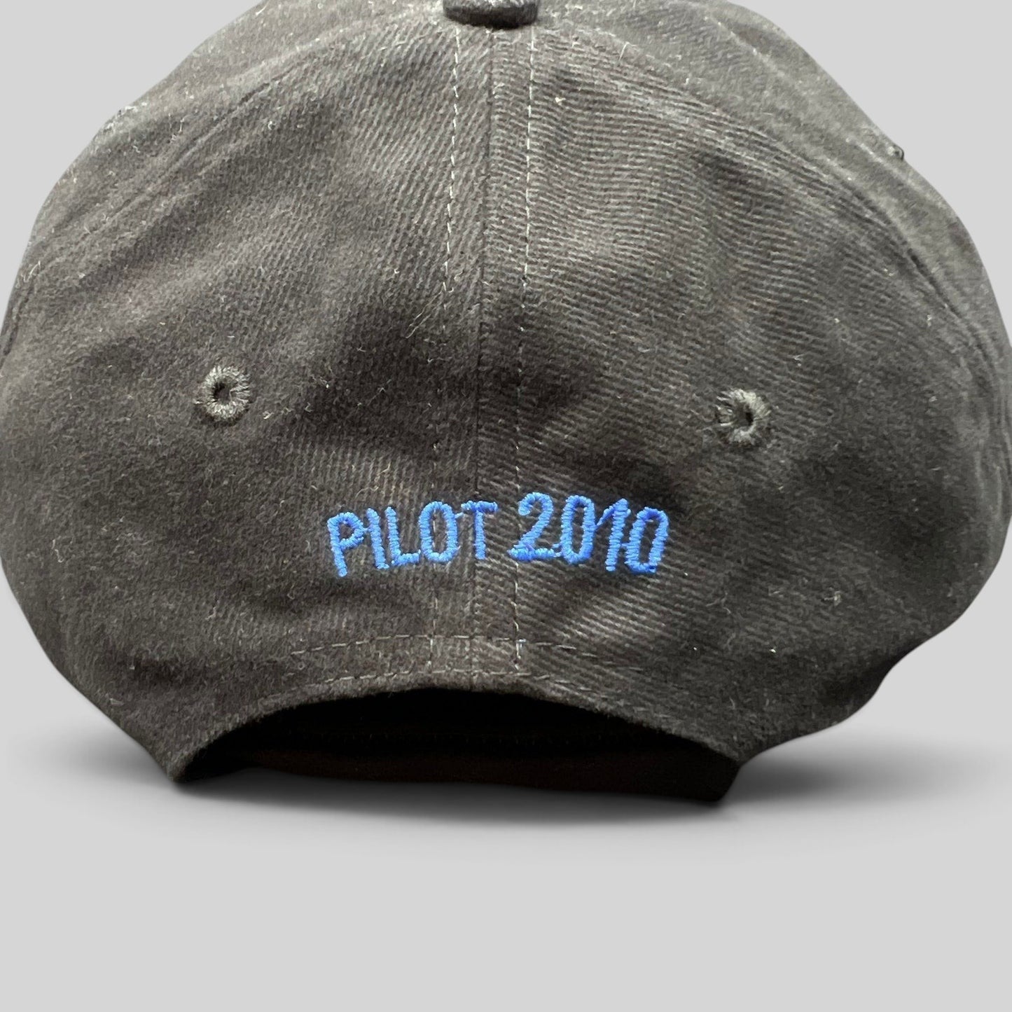 Raree Finds black cotton crew hat with blue embroidered text reading PILOT 2010 on the back panel