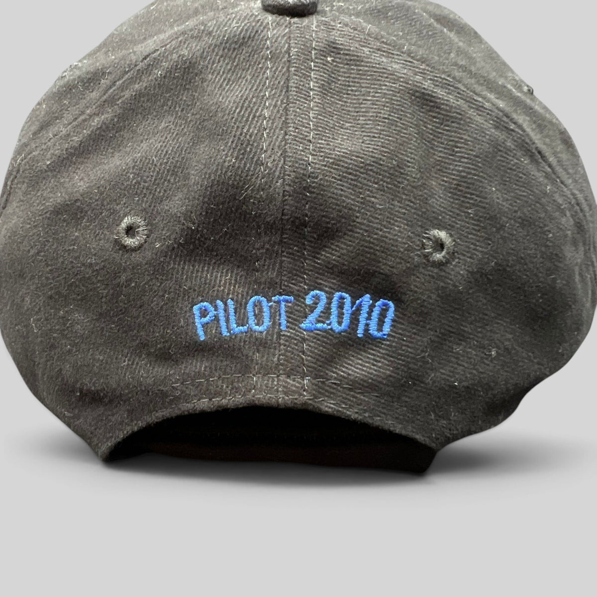 Raree Finds black cotton crew hat with blue embroidered text reading PILOT 2010 on the back panel
