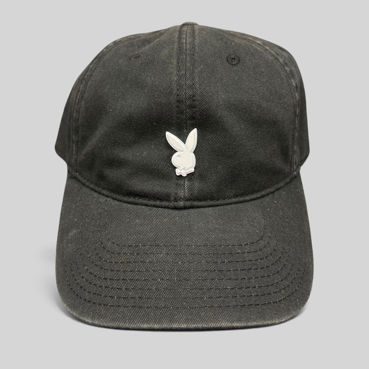 Raree Finds black strapback hat featuring a minimalist silver metal Playboy bunny logo on the front crown.