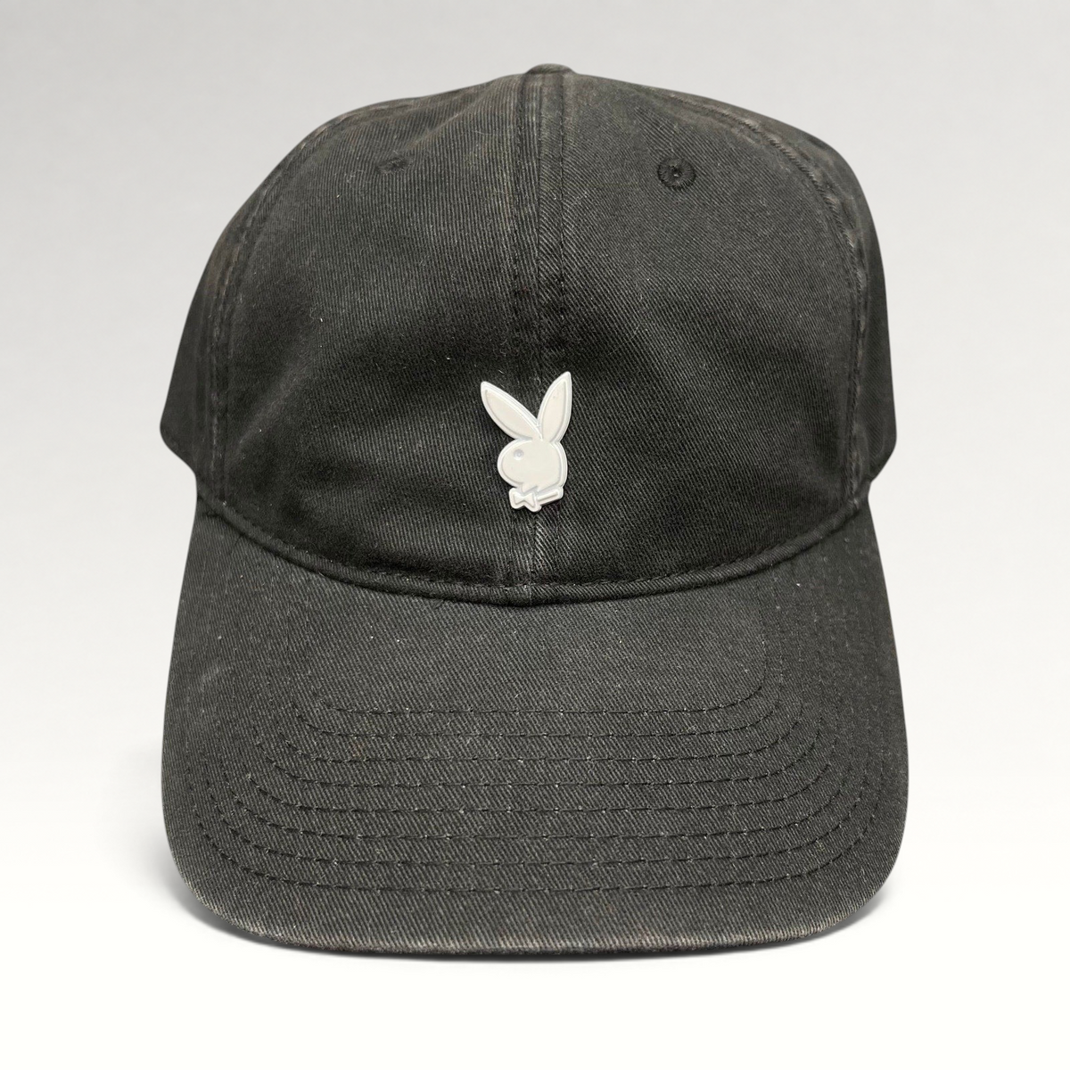 Raree Finds black strapback hat featuring a minimalist silver metal Playboy bunny logo on the front crown.