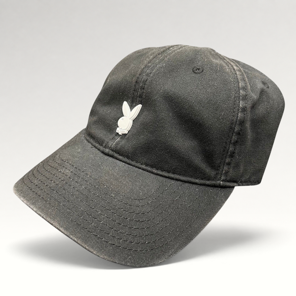 Raree Finds black cotton strapback hat featuring a minimalist raised metal Playboy bunny logo on the front crown.