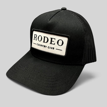 Raree Finds black snapback trucker hat with a white embroidered Rodeo Country Club patch and breathable mesh back.