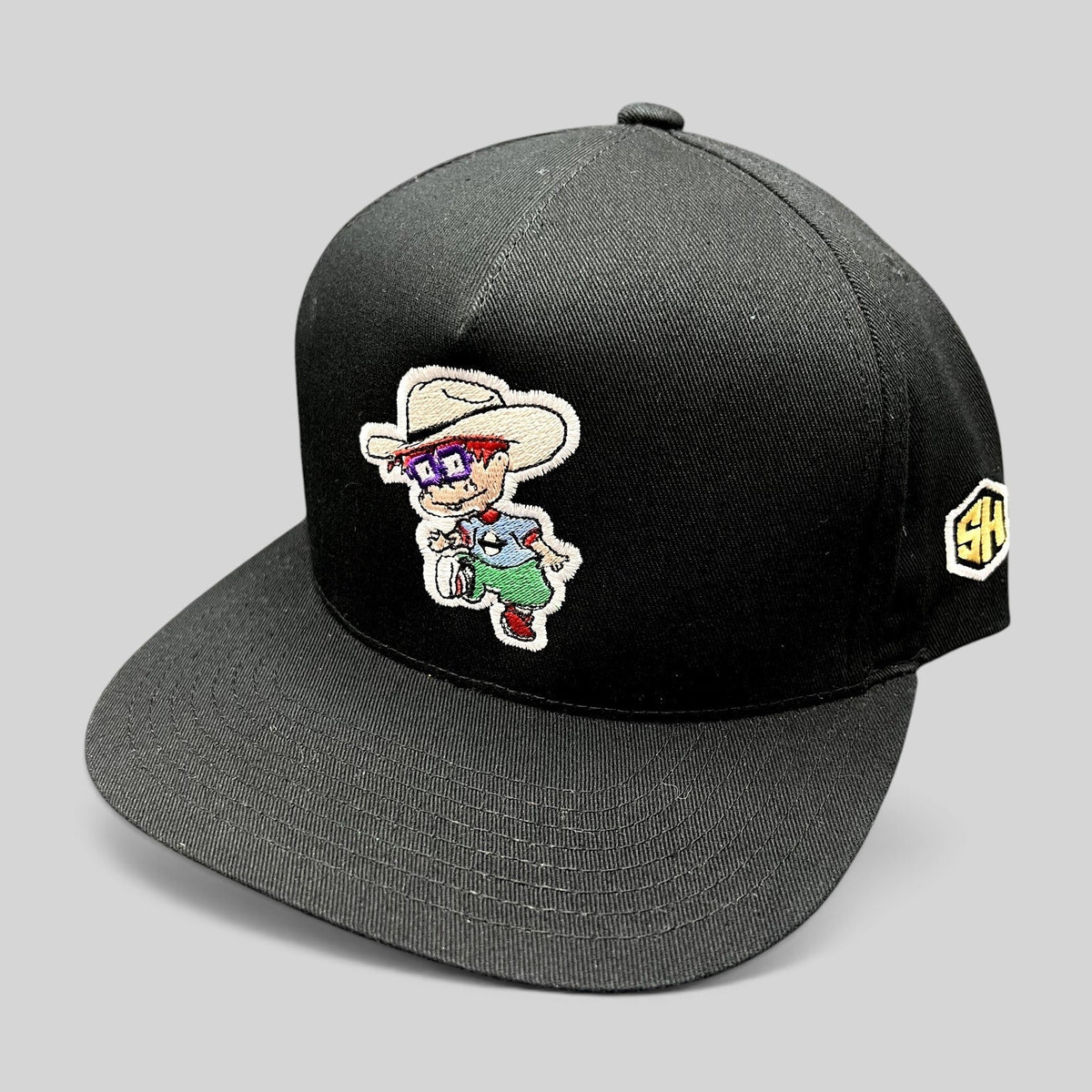 Raree Finds black Yupoong cotton snapback hat with embroidered Rugrats-style character and flat brim design