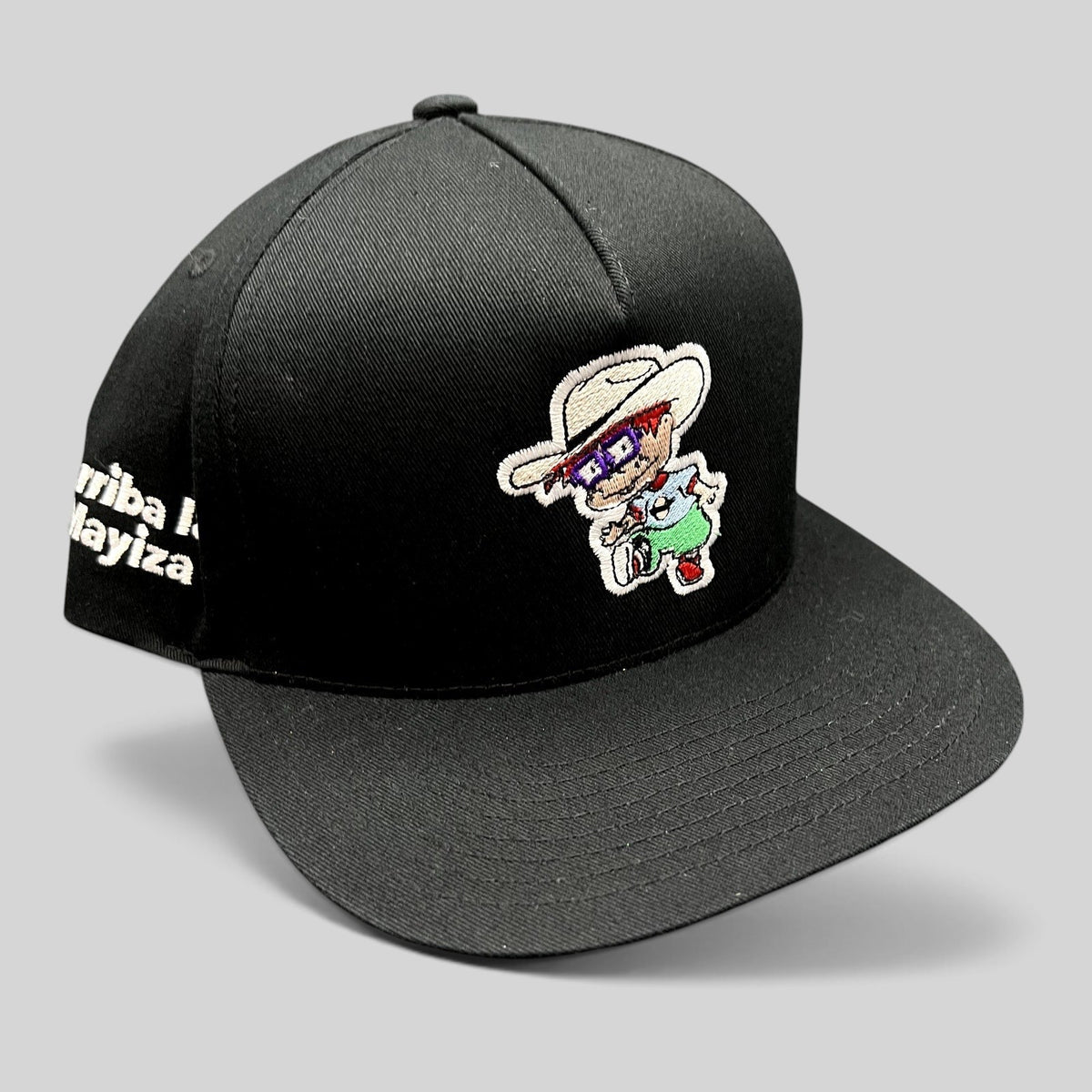 Raree Finds black Yupoong snapback hat featuring a Rugrats-inspired embroidered character and Arriba La Mayiza text.