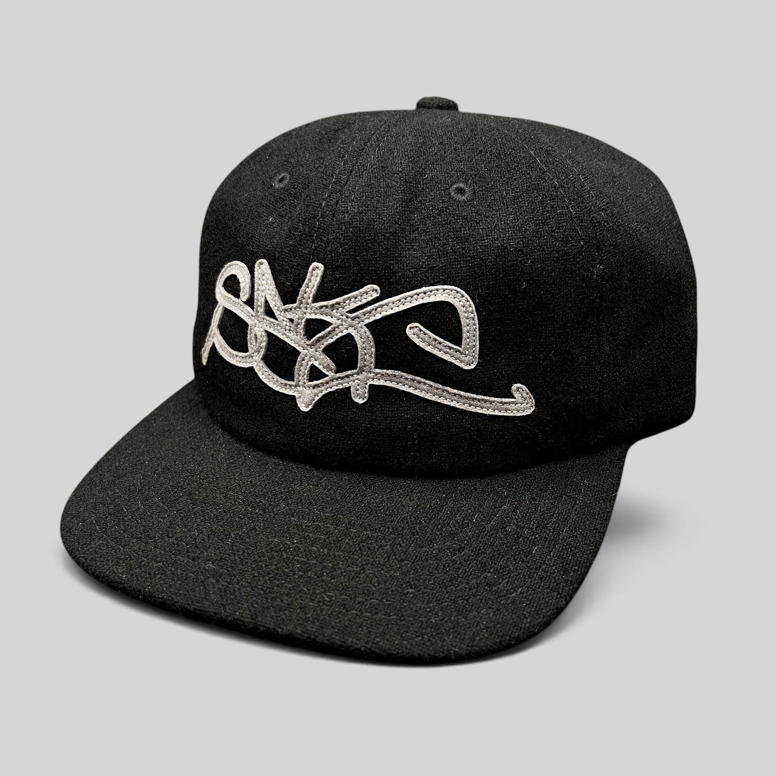 Raree Finds black Sake Brand strapback hat with oversized gray embroidered script logo and flat brim streetwear design.