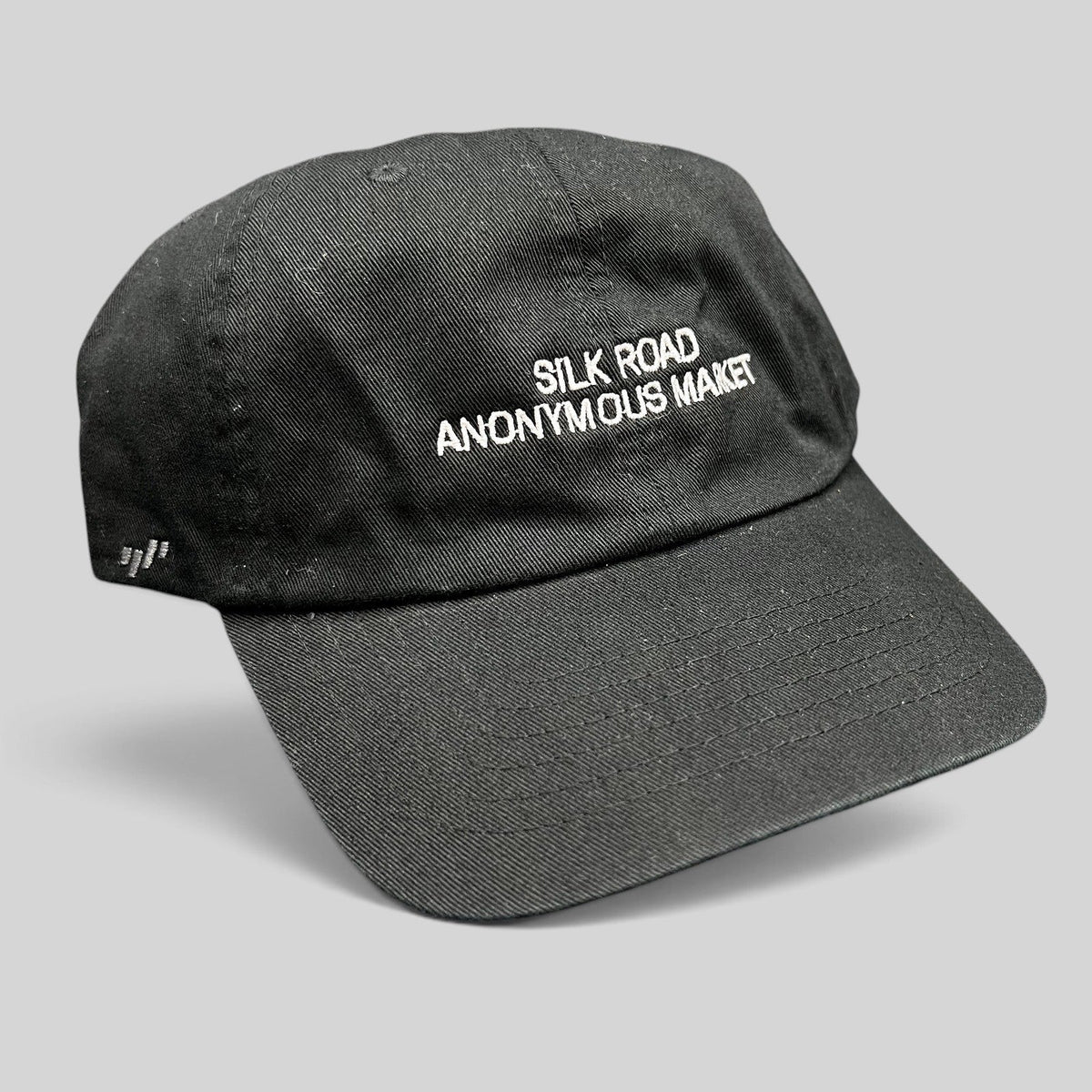 Raree Finds black Yupoong dad cap with white Silk Road Anonymous Market embroidery and adjustable strapback closure.