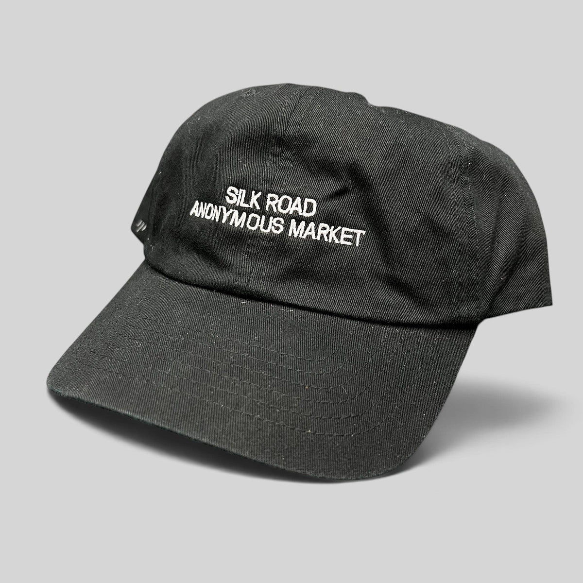 Raree Finds black Yupoong dad cap with white Silk Road Anonymous Market embroidery and adjustable strapback closure.