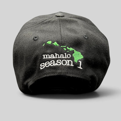 Rear view of a Raree Finds black snapback hat featuring embroidered Mahalo Season 1 text and a green Hawaiian island