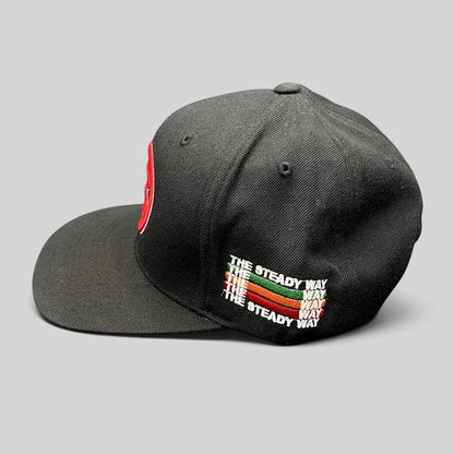 Raree Finds black Yupoong snapback hat with side embroidery reading The Steady Way in red, green, and white text.