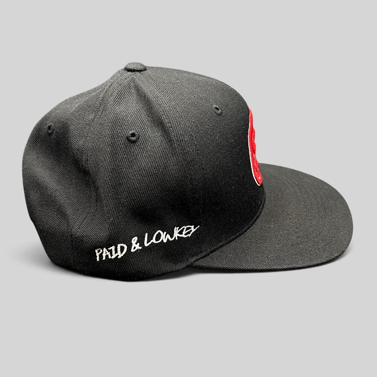 Raree Finds black Yupoong snapback hat with red front logo and white Paid & Lowkey side embroidery