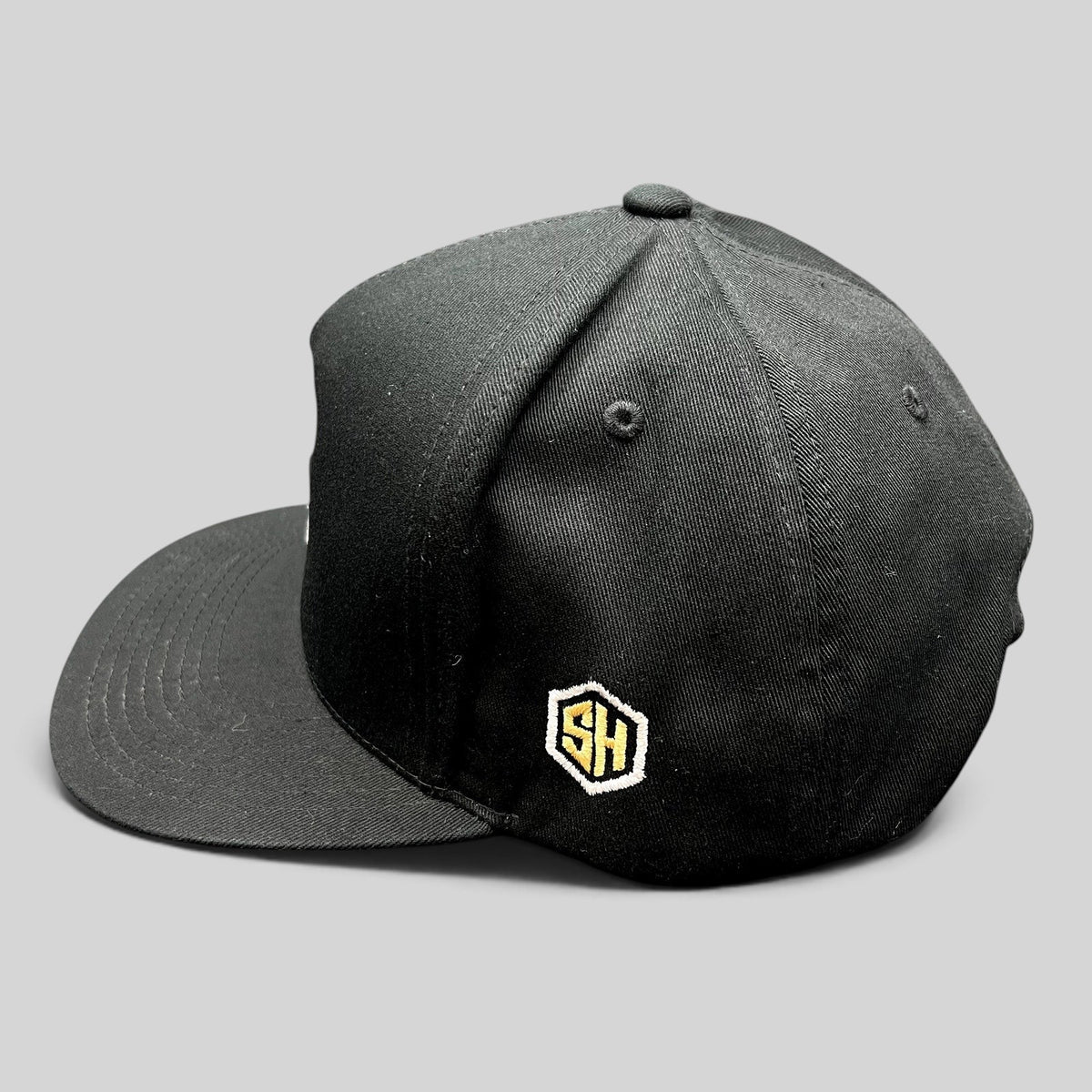 Raree Finds black Yupoong cotton snapback hat featuring side SH hexagon embroidery and structured flat brim design