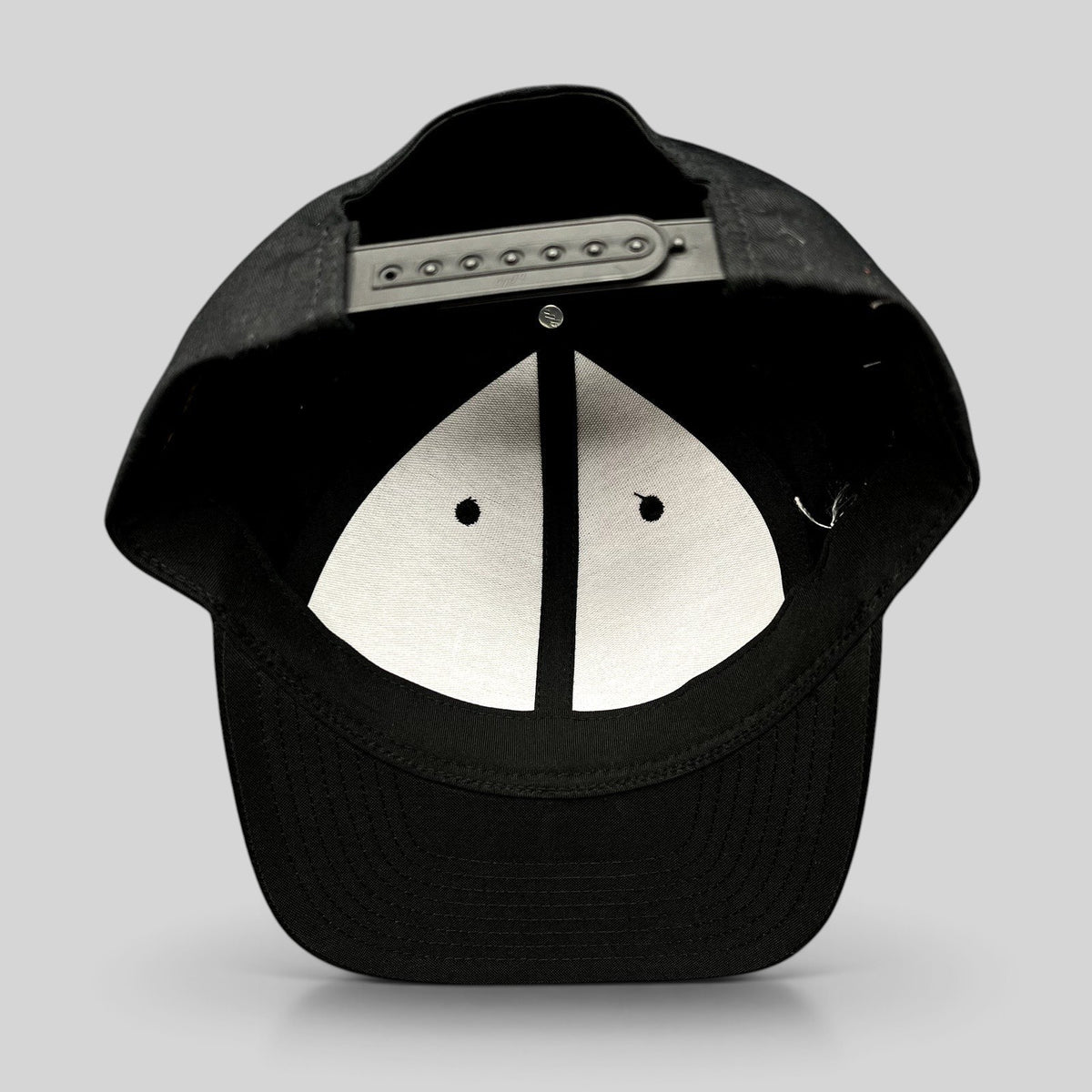 Raree Finds black Yupoong Classics snapback hat showing the interior adjustable strap and white crown lining