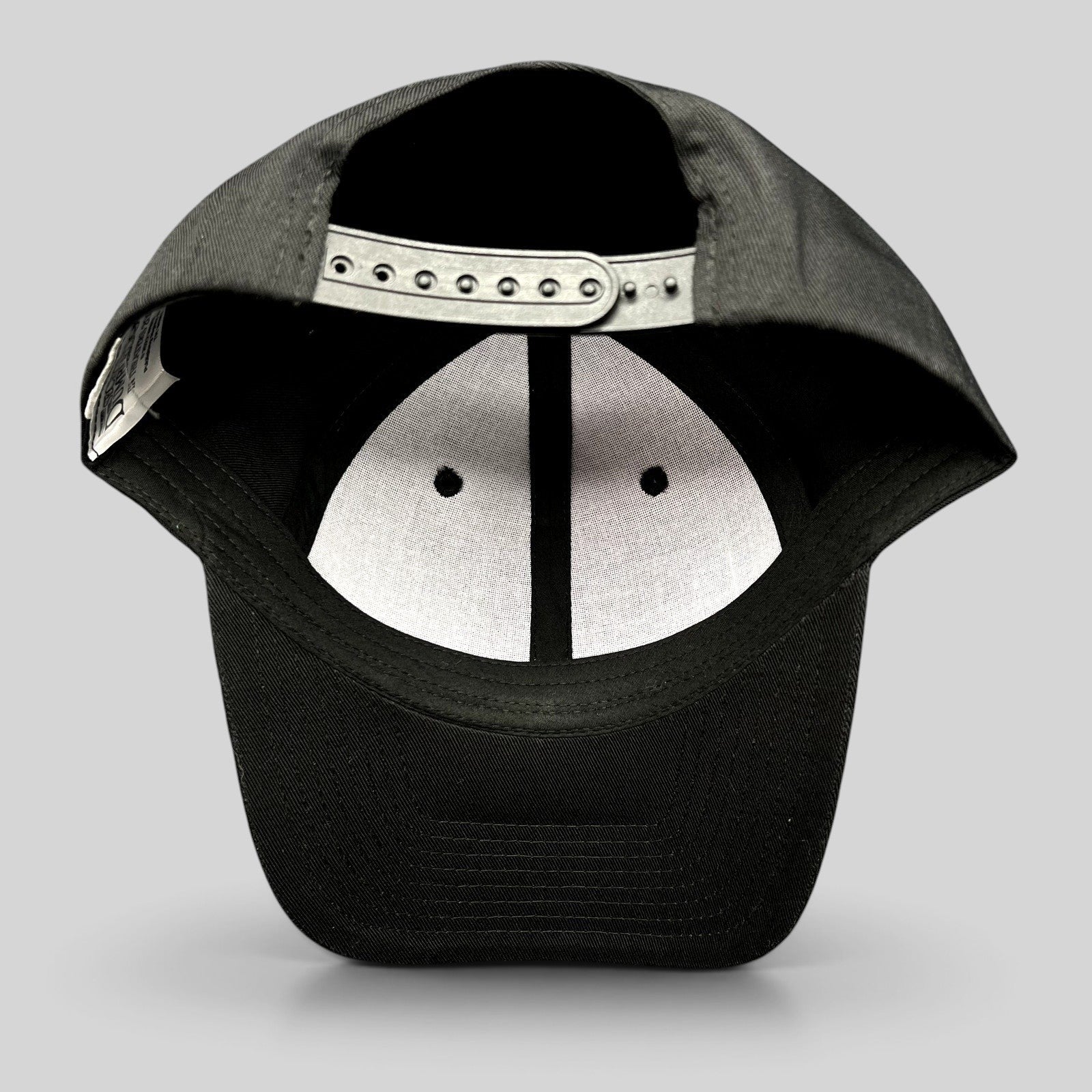 Raree Finds black snapback hat showing the interior adjustable plastic strap and white crown lining